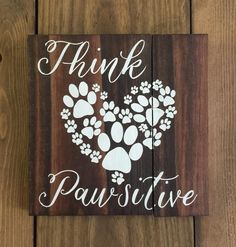 a wooden sign that says think pawstuve with paw prints in the shape of a heart