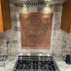 a stove top oven sitting inside of a kitchen next to a wall with a tree on it