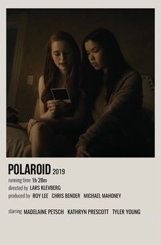 two women sitting next to each other on a bed in front of a poster for polaroid