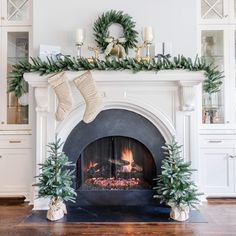 a fireplace decorated with christmas stockings and greenery