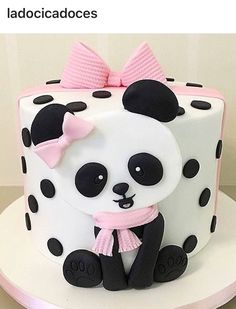 a panda bear cake is decorated with black and white polka dots, pink ribbon, and bow