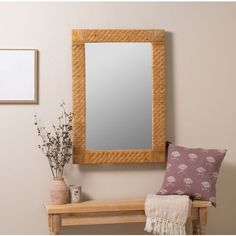 a wooden mirror hanging on the wall above a bench