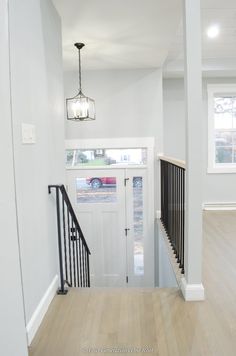 an empty hallway with white walls and black railings on the second floor, leading to a front door