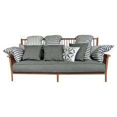 a couch with many pillows on it sitting next to a white wall and wooden frame