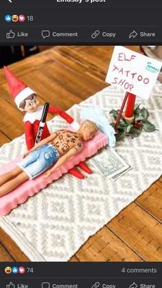 an elf laying on top of a fake man with a sign in front of him