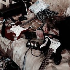 a man laying on top of a bed next to an electric guitar