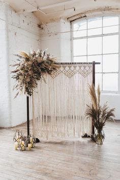 an arrangement of flowers and plants in front of a white wall hanging from the ceiling