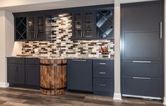 a kitchen with gray cabinets and marble counter tops, along with dark wood flooring