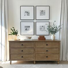 three framed pictures hang on the wall above a dresser with two vases and one potted plant