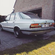 a white car parked in front of a brick building next to a green lawn area