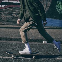 a man riding a skateboard down a street next to a graffiti covered wall with writing on it