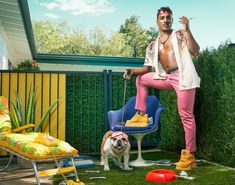 a man sitting on top of a blue chair next to a dog and wearing yellow shoes