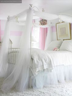 a white canopy bed with pink and white curtains