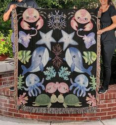 two people standing next to a large quilt with sea animals on it and under the stars