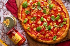 a pizza sitting on top of a wooden cutting board next to a jar of mustard