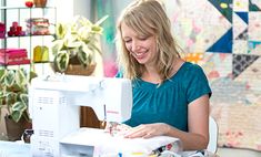 a woman is smiling as she sews on a sewing machine