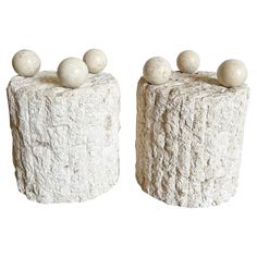 two pieces of white marble with balls on top and one piece made out of rock