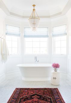 a bathroom with a rug, chandelier and bathtub in the middle of it