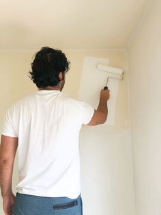 a man is painting the wall with white paint