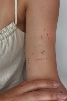 two hands holding each other with small stars on the back of their arm and wrist