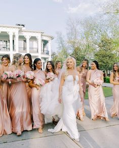 a group of women standing next to each other in front of a white and pink building