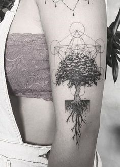 a black and white photo of a woman's arm with a tree tattoo on it