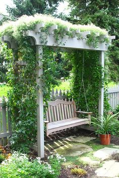 a wooden bench sitting under a lush green arbor