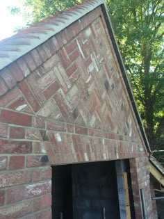 an old brick building with a black door and window on the side, in front of some trees