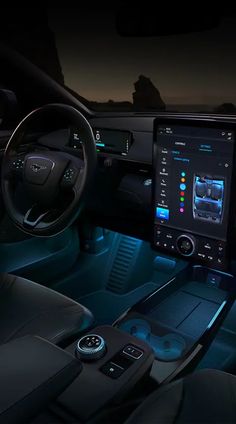 the interior of a modern car with touchscreens and steering wheel controls at night