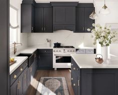 a kitchen with black cabinets and white counter tops, an area rug on the floor