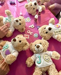 a group of teddy bears sitting on top of a table covered in pink cloths