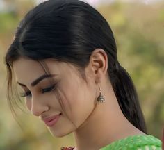 a close up of a person wearing some kind of earring and looking down at something