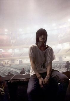 a man sitting on top of a wooden bench in front of an empty stadium filled with people