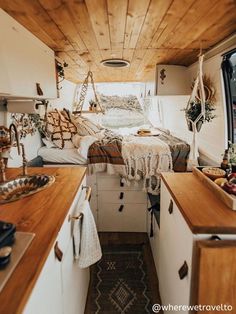 the interior of a camper with wood flooring and white walls, including a bed