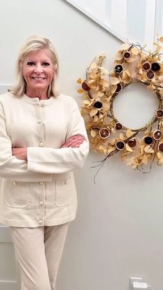 a woman standing in front of a wreath with her arms crossed next to the door