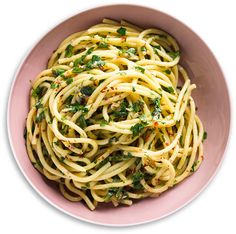 a pink bowl filled with pasta and greens