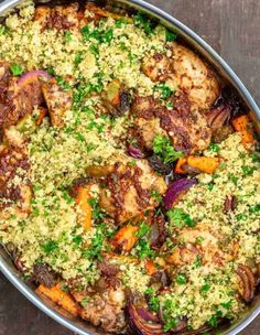 a pan filled with chicken, carrots and couscous on top of a table