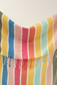 a multicolored towel with fringes hanging from it's side on a white wall