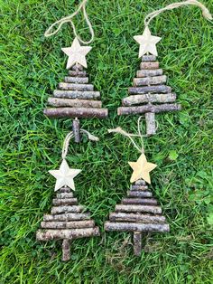 three wooden christmas trees made out of logs and stars on green grass with twine string