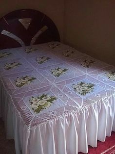 the bed is made with white bedspread and flowers on it's edges