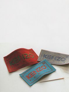 three different types of luggage tags sitting on top of a white surface with the word kenzo printed on them