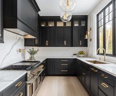 a kitchen with black cabinets and white counter tops, gold pulls on the handles in front of the stove