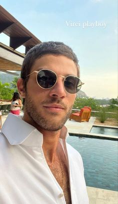 a man wearing sunglasses standing in front of a pool