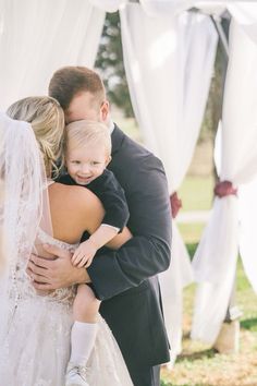 a man and woman hugging each other in front of a wedding arch