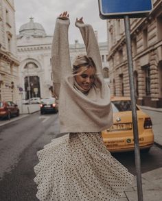 a woman standing on the street with her arms in the air