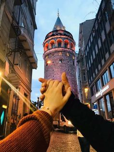 two people reaching out their hands to touch each other in front of an old building