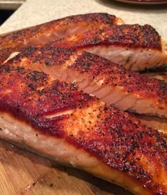 two pieces of meat sitting on top of a wooden cutting board