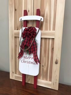 a wooden sled with a red bow and merry christmas sign attached to the sled