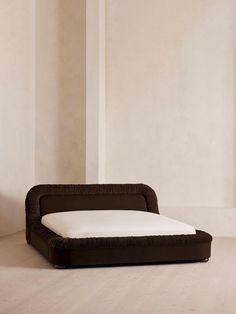 a brown and white bed sitting on top of a wooden floor