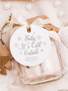 a baby it's cold outside gift in a glass jar next to wooden ornaments